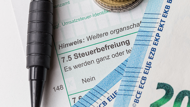 Ausschnitt eines Steuerformulars mit Stift und Bargeld.